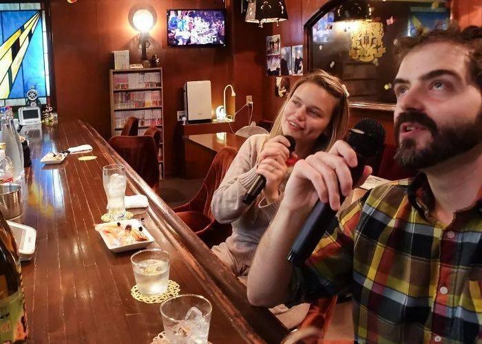 Two guests of a Fukuoka snack bar tour joining in with karaoke.